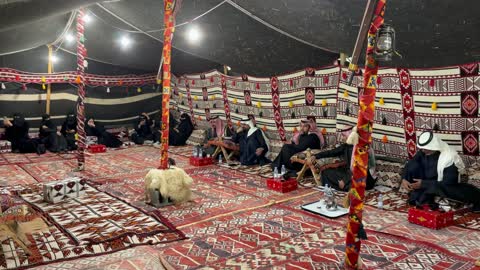 الضيافة العربية الأصيلة، سجاد وبسط تقليدية بألوان حمراء ونقوش ، مجلس عربي تقليدي في الممكلة العربية السعودية، الرجال والنساء يجلسون في مجموعات منفصلة، الأواني التقليدية لتقديم القهوة أو الشاي، الأعمدة الخشبية تدعم هيكل الخيمة