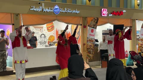 رقص شعبي تقليدي امام احدى المطاعم فى القرية العالمية فى المنطقة الشرقية، المملكة العربية السعودية، يوم 29 من ديسمبر 2025 ، علامات تجارية محلية وعالمية ، أنشطة عائلية وتجارب تفاعلية، فعالية ثقافية وترفيهية متكاملة،  التنوع الثقافي والترفيه