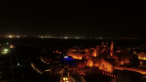 A famous Saudi cultural, tourist, and historical center and landmark at night, the illuminated Al-Bujairi Park and overlook during the day, the cultivation of plants and green palm trees, the development project of historical Diriyah in the city of Riyadh, Saudi Arabia, the heritage village and archaeological buildings.