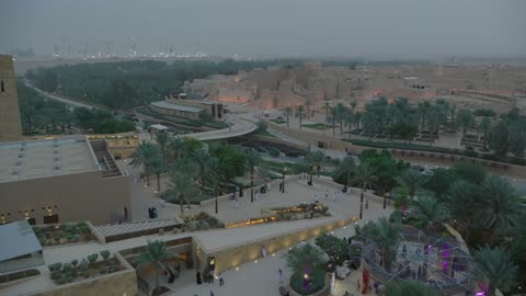 The illuminated Al-Bujairi Park and overlook during the day, planting of plants and green palm trees, the development project of historic Diriyah in the city of Riyadh, Saudi Arabia, a well-known cultural, tourist, and historical landmark, the heritage village and archaeological buildings.