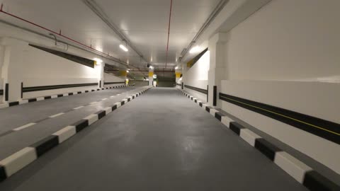 أسقف عالية وأعمدة زرقاء، نظام توجيه آلي لمواقف السيارات، مرآب حديث تحت الأرض متعدد الطوابق في المملكة العربية السعودية، تُستخدم هذه المرافق في المراكز التجارية الكبرى أو المطارات أو الأماكن العامة