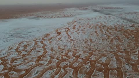 جبال مغطا بالثلوج وتشكيلات جبلية، معالم حضارية سياحية في المملكة العربية السعودية، سماء ملبدة بالغيوم ، أجواء الثلجية الباردة، سلسلة حائل عروس الشمال تكسوها الثلوج، تصوير درون جوي للتكوينات الصخرية