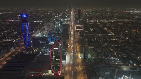 The architectural engineering art in the modern style of towers and skyscrapers in the city of Riyadh, the lifestyle in the capital, urban growth, development, and progress, drone photography of the SABB Bank Tower at night, the famous buildings and commercial landmarks in the Kingdom of Saudi Arabia, King Fahd Road.