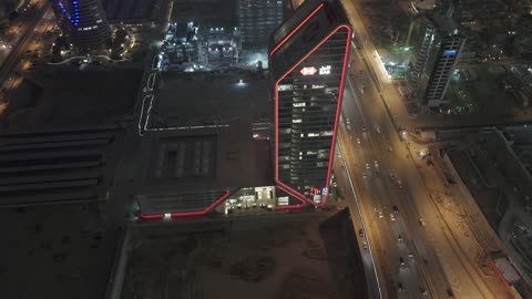 The architectural engineering art in the modern style of towers and skyscrapers in the city of Riyadh, the lifestyle in the capital, urban growth, development, and progress, drone photography of the SABB Bank Tower at night, the famous buildings and commercial landmarks in the Kingdom of Saudi Arabia, King Fahd Road.