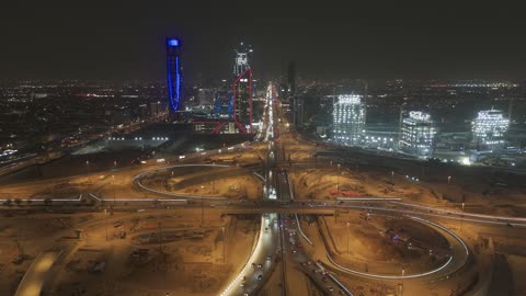 The architectural engineering art in the modern style of towers and skyscrapers in the city of Riyadh, the lifestyle in the capital, urban growth, development, and progress, drone photography of the SABB Bank Tower at night, the famous buildings and commercial landmarks in the Kingdom of Saudi Arabia, King Fahd Road.