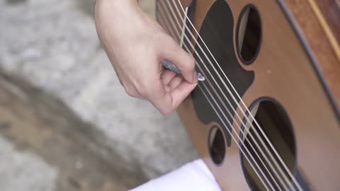 Mastering the art of musical performance, a close-up shot of a professional Saudi Gulf Arab musician sitting and playing the oud.