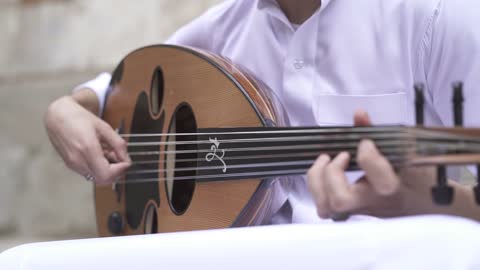 Mastering the art of musical performance, a close-up shot of a professional Saudi Gulf Arab musician sitting and playing the oud.