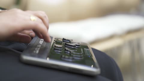 توفير اجهزة تساعد ذوي الهمم، تصوير مقرب لامرأة عربية خليجية سعودية ترتدي عباءة سوداء كفيفة تقوم بالقراءة باستخدام جهاز برايل الإلكتروني