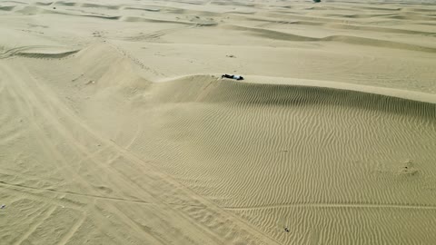 الرمال الذهبية الناعمة، تصوير درون لرجل عربي خليجي سعودي يسير وسط الصحراء في مكة في المملكة العربية السعودية
