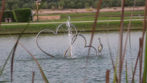 شكل قلب خشبي مع نافورة في حديقة بحيرة الحب بدبي، الإمارات العربية المتحدة، في يوم مشمس