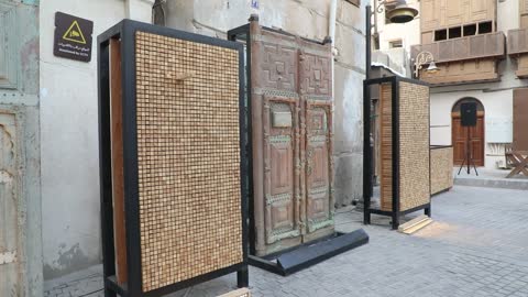 An exhibition of traditional carved wooden doors and contemporary art in the Al-Balad district of Jeddah, featuring old-style geometric art, a famous historical place in the Kingdom of Saudi Arabia.