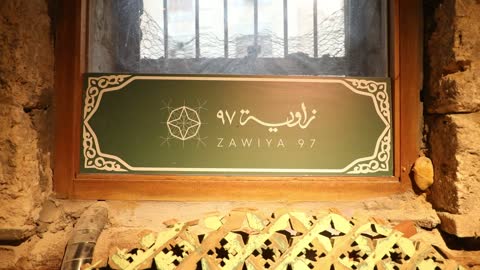 A close-up shot of the sign for the Zawiya 97 cultural project in the historic Al-Balad district of Jeddah, Saudi Arabia.
