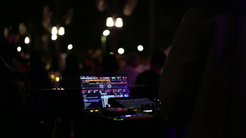 A close-up shot of a professional DJ mixing music at a night party, having a fun and entertaining time.