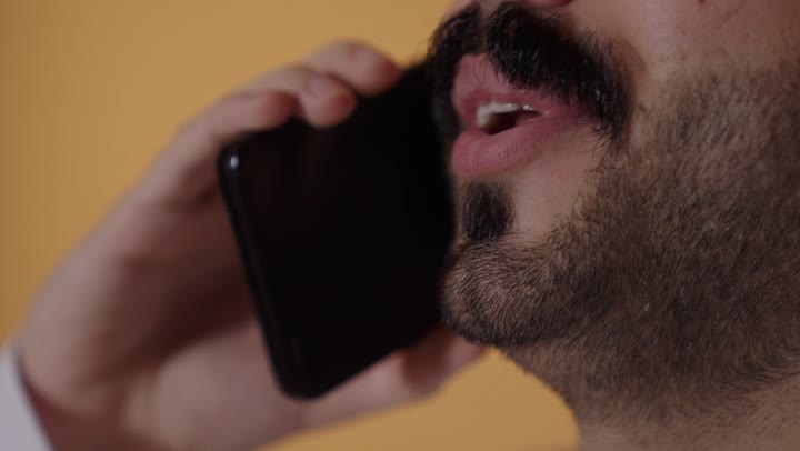 ايماءات السعادة و السرور، التواصل مع الاهل و الاصدقاء، بورتريه مقرب لرجل عربي خليجي عماني  يقوم بإجراء مكالمة هاتفية عبر الهاتف المحمول، استخدام التقنيات الحديثة المتطورة, خلفية برتقالية