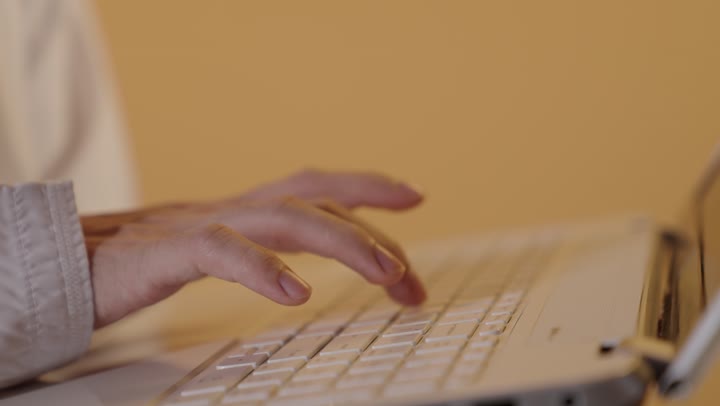 تسجيل الملاحظات المهمة, مهن و وظائف مكتبية, استخدام الأجهزة التقنية الحديثة لإنجاز الأعمال, بورتريه ليدين رجل عربي خليجي عماني يقوم بالنقر على لوحة المفاتيح, خلفية برتقالية