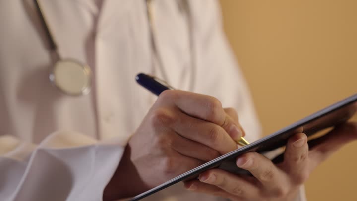 تقديم الخدمات والاستشارات الطبية للمراجعي، بورتريه مقرب ليد لطبيب عربي خليجي عماني يقوم بتدوين نتائج الفحوصات بالسجل الطبي، إعداد التقارير الطبية، مفهوم الطب والرعاية الصحية، خلفية برتقالية