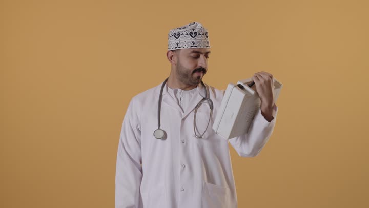 تقديم الخدمات الصحية الطارئة للمرضى، مبادئ التعامل مع حالات الطوارئ، بورتريه  لطبيب عربي خليجي عماني يرتدي الزي التقليدي والمعطف يحمل بيده حقيبة الاسعافات الأولية، الأدوات والمعدات الطبية اللازمة، العمل في القطاع الصحي، خلفية برتقالية