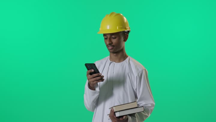 مهندس عربي يستخدم الهاتف الذكي والكتب أمام خلفية خضراء
