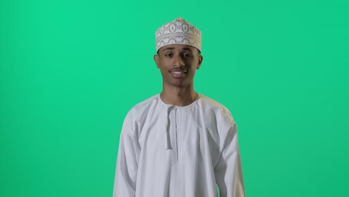 شاب عماني يشير بالإبهام خلفية خضراء