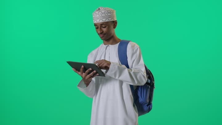 طالب عُماني يستخدم جهاز لوحي بخلفية خضراء