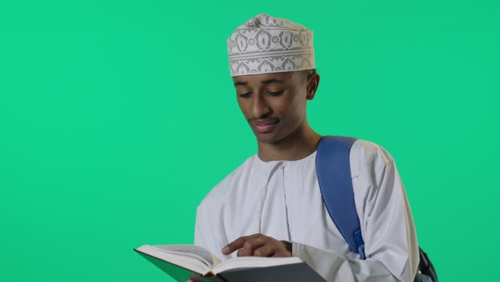 طالب عُماني يقرأ كتاباً أمام خلفية خضراء كروما