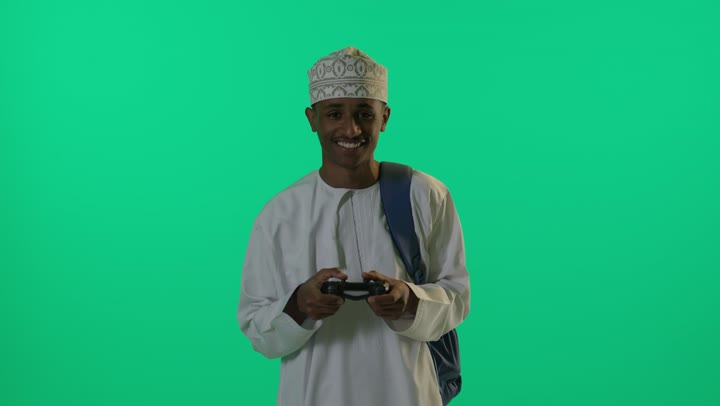 لاعب عماني يمسك وحدة تحكم على خلفية خضراء