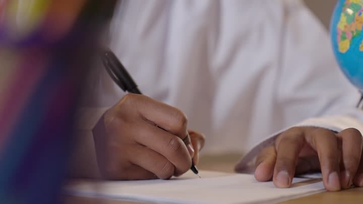 A close-up shot of an Omani man writing on paper.