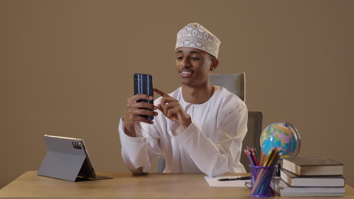 Omani Young Man Using Smartphone at Office Desk