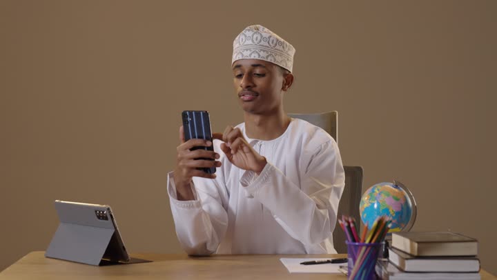 شاب عماني يستخدم الهاتف الذكي في المكتب