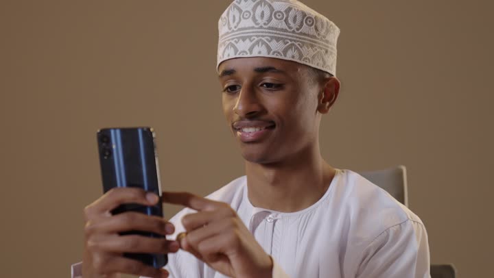 Omani Man Wearing Traditional Dress Using Smartphone
