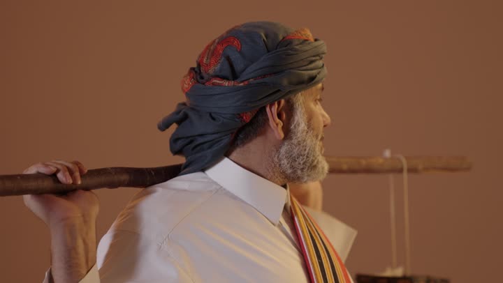 سقاي الماء يقوم بالتجول لسقي الناس من البئر، ارتداء ازياء المنطقة الجنوبية، تأسيس الدولة السعودية الاولى 22فبراير، يوم بدينا 1727م، بورتريه لرجل كبير بالسن عربي خليجي سعودي يرتدي الثوب والغترة والشال الجنوبي يحمل دلو من الجلد,  خلفية بيج