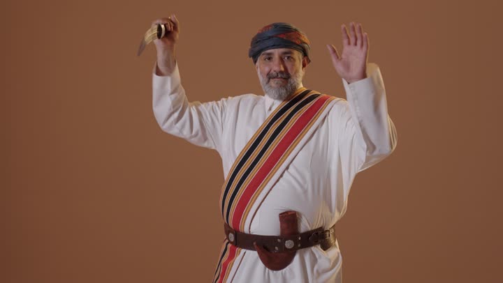 ارتداء أزياء المنطقة الجنوبية للاحتفال في المناسبات الوطنية، يوم بدينا 1727م، بورتريه لرجل كبير بالسن عربي خليجي سعودي مبتسم يرتدي الثوب والغترة مع الشال الجنوبي يرقص ويحتفل يحمل بيده سيف ، ذكرى تأسيس الدولة السعودية الأولى 22 فبراير، خلفية بيج