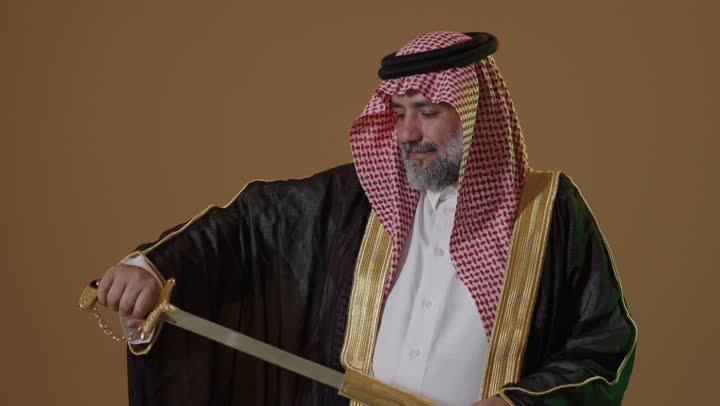 ذكرى تأسيس الدولة السعودية الأولى1727م,  مفهوم حب الوطن والانتماء اليه, يوم بدينا 22 فبراير, ارتداء الزي الشعبي في مناسبة وطنية, بورتريه من الجانب لرجل كبير بالسن عربي خليجي سعودي يرتدي البشت والعقال يمسك بيده السيف، خلفية بيج