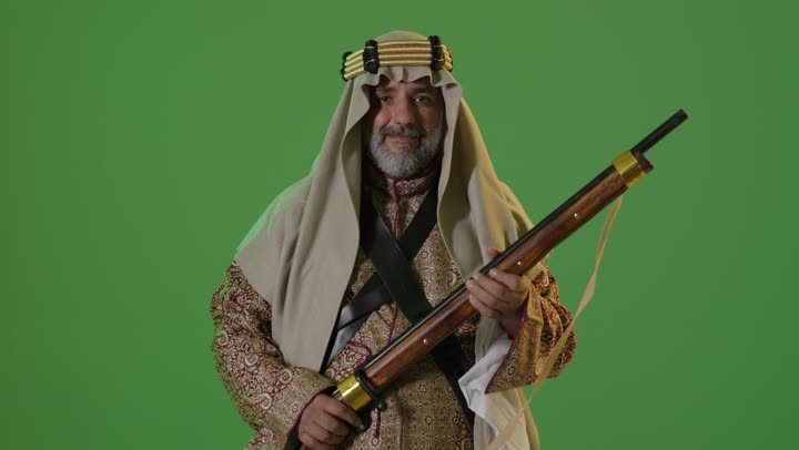 Wearing traditional attire on a national occasion, the anniversary of the establishment of the first Saudi state in 1727, the concept of love for the homeland and belonging to it, the day we started, February 22, a portrait of an elderly Arab Gulf Saudi man wearing a bisht and agal standing and holding a Saudi rifle, green background, chroma.