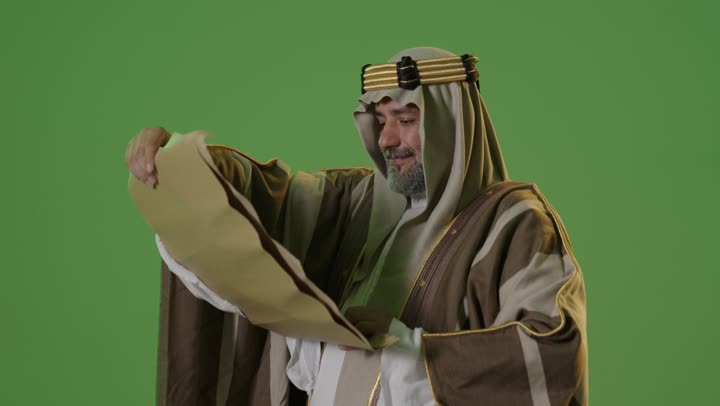 Anniversary of the establishment of the first Saudi state in 1727, the authenticity and heritage of the Arabs, the concept of love for the homeland and belonging to it, the day we started on February 22, wearing traditional attire on a national occasion, a portrait of an elderly Arab Gulf Saudi man wearing traditional thobe and agal reading a historical leather manuscript, green background, chroma.