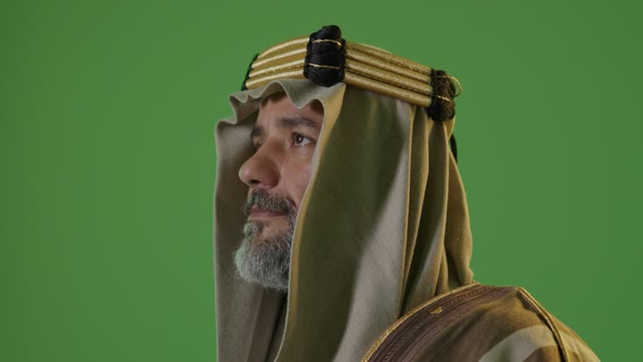 A side portrait of an elderly Arab Gulf Saudi man wearing a bisht and agal, looking with expressions of pride, commemorating the founding of the first Saudi state in 1727, the concept of love for the homeland and belonging to it, the day we started on February 22, wearing traditional attire on a national occasion, with a green background, chroma.
