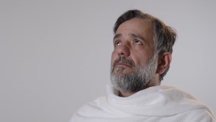 رجل عربي بملابس الإحرام يدعو الله في الاستوديو