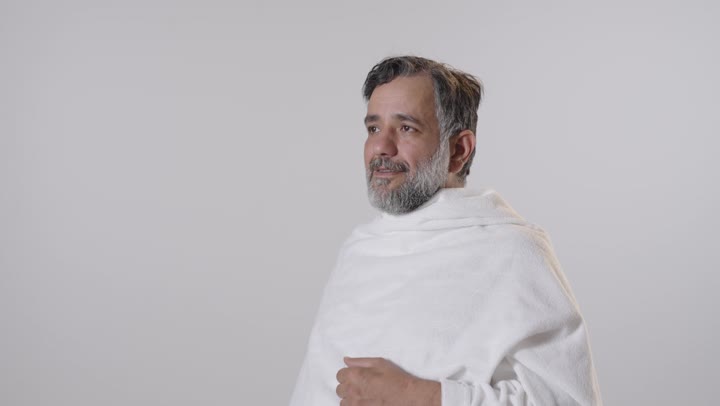 رجل بملابس الإحرام يشرب الماء في الاستوديو