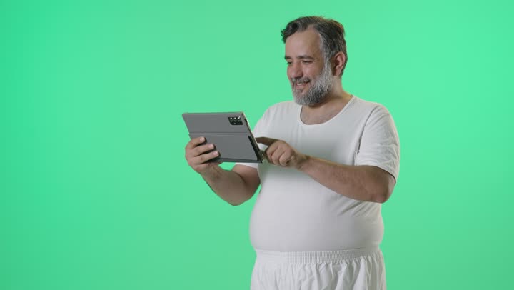 رجل عربي يستخدم جهاز لوحي أمام خلفية خضراء