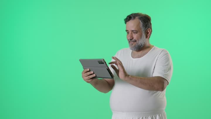 رجل عربي يستخدم جهاز لوحي رقمي أمام خلفية كروما خضراء