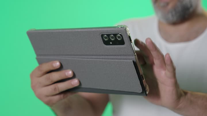 رجل يستخدم جهازاً لوحياً أمام خلفية خضراء