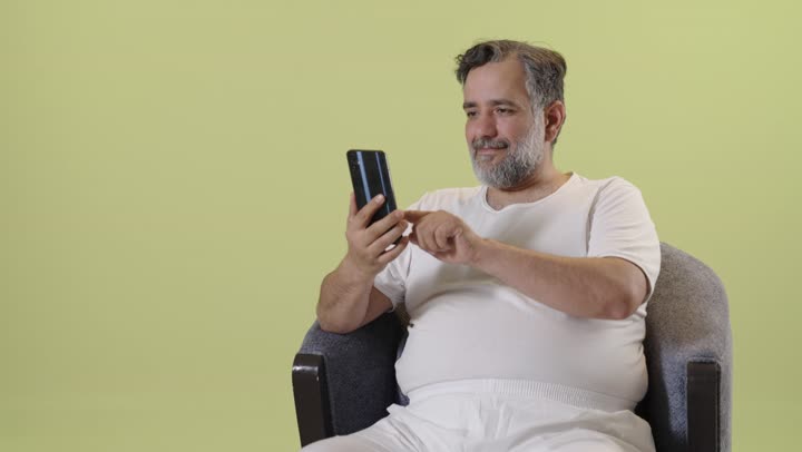 رجل عربي يستخدم الهاتف الذكي أمام خلفية صفراء