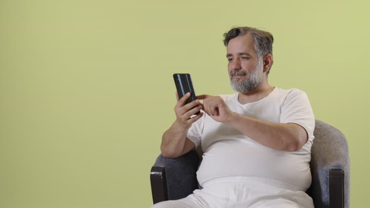 رجل عربي في منتصف العمر يستخدم الهاتف الذكي بخلفية صفراء