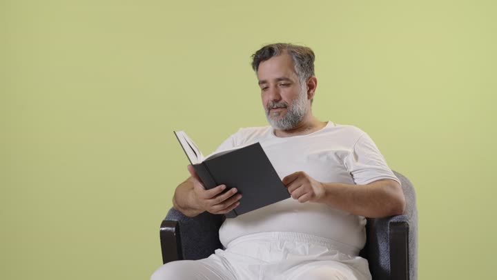 رجل عربي في منتصف العمر يقرأ كتاباً بخلفية صفراء