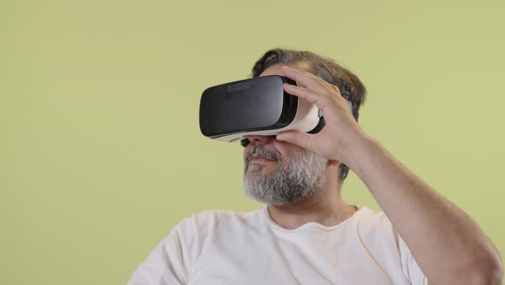 An Arab man wearing virtual reality glasses with a yellow background.