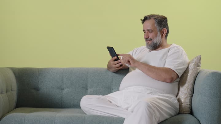Arab Man Using Smartphone on Sofa Indoor