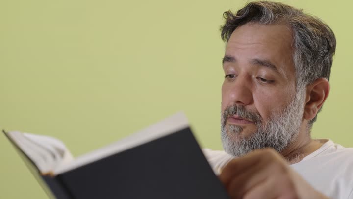 رجل عربي يقرأ كتاباً لقطة قريبة خلفية صفراء