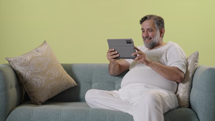 Middle Aged Arab Man Using Tablet on Sofa