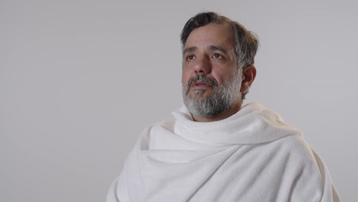 رجل عربي بملابس الإحرام يمسك مسبحة