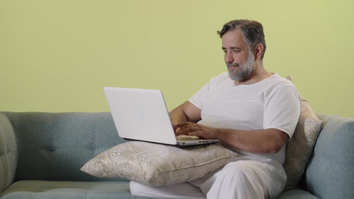 Middle Aged Arab Man Using Laptop on Sofa